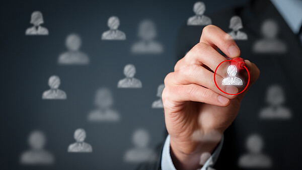 Männliche Hand, die mit einem roten Stift auf einer Glasscheibe einen Kreis um eine virtuelle Person zeichnet