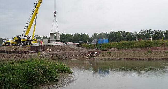 Baustelle des ersten Einlassbauwerks für den Hochwasserrückhalteraum Breisach-Burkheim am Rein Autokran hebt Fertig-Betonteile für das Einlassbauwerk in die Baugrube