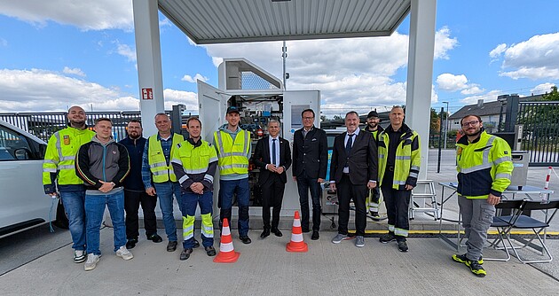 Personen in der Mitte v.l.n.r: Herr Dr. Patrick Rapp, Staatssekretär des Ministeriums für Wirtschaft, Arbeit und Tourismus, Herr Regierungspräsident Klaus Tappeser, Herr Uwe Alle, Abteilungspräsident der Abteilung 10 – Landesbetrieb Eich- und Beschusswesen des Regierungspräsidiums Tübingen, gemeinsam mit den Kollegen der Abteilung 10 und der Firma H2-MOBILITY vor Ort bei einer Wasserstofftankstelle in Heidelberg
