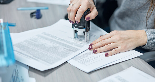 Beglaubigung von Urkunden Frau am Schreibtisch, die eine Urkunde beglaubigt