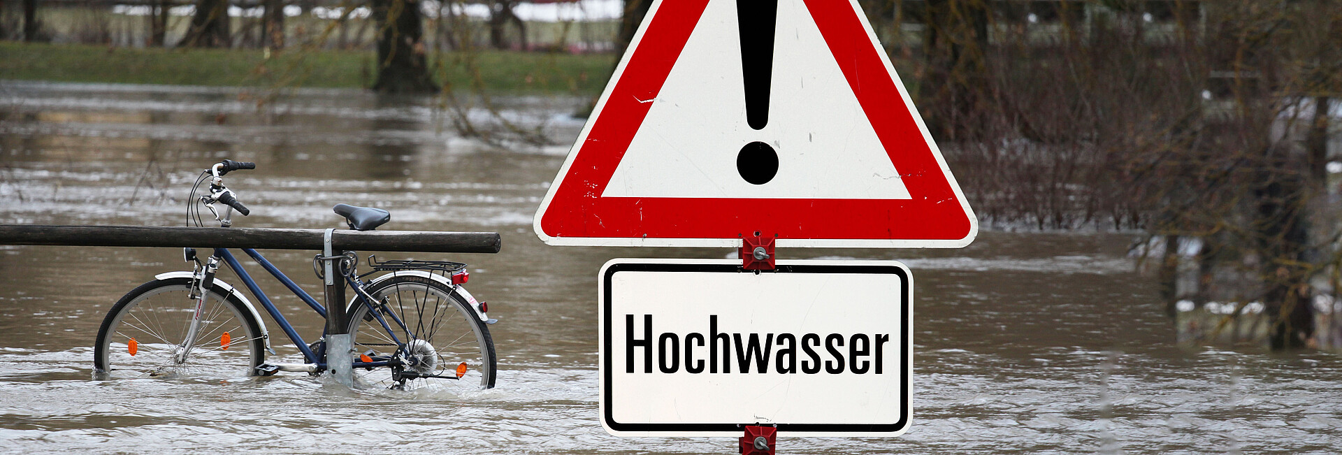 Hochwasser-Warnschild mit überfluteter Fläche im Hintegrund Bild zeigt Hochwasser-Warnschild mit überfluteter Fläche im Hintegrund