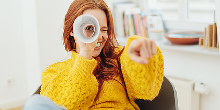 Frau schaut durch eine Papierrolle Frau schaut durch eine Papierrolle und spielt Spion